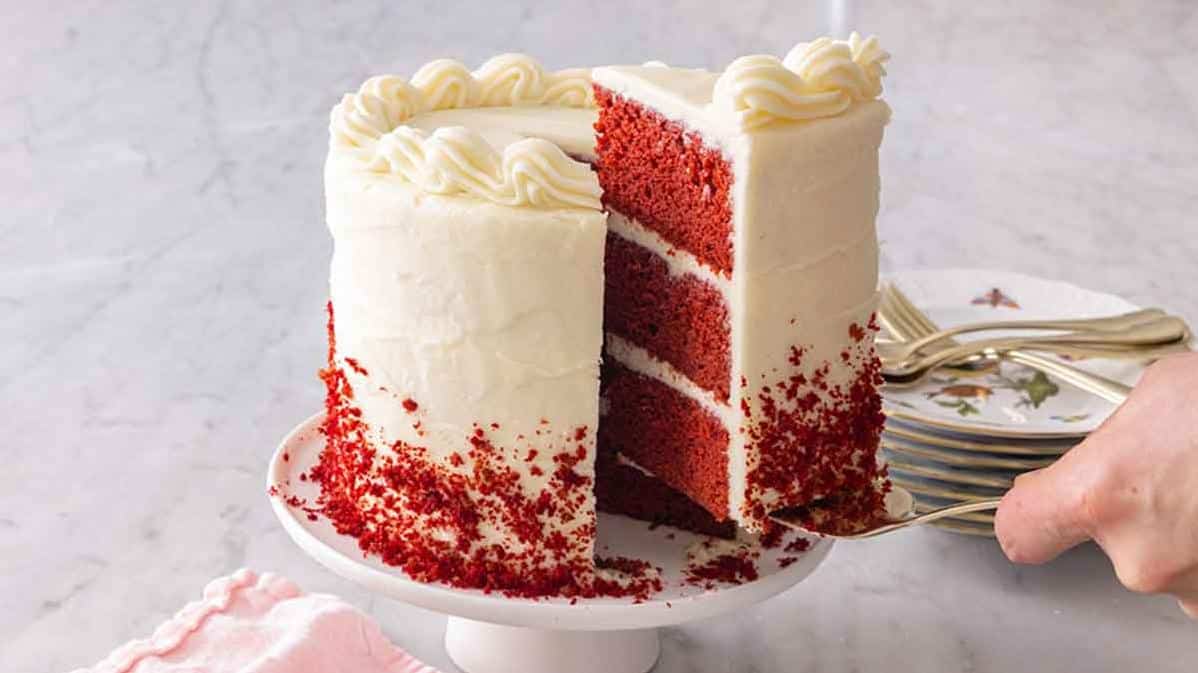  The vibrant red color of the cake is the perfect backdrop for the creamy white icing